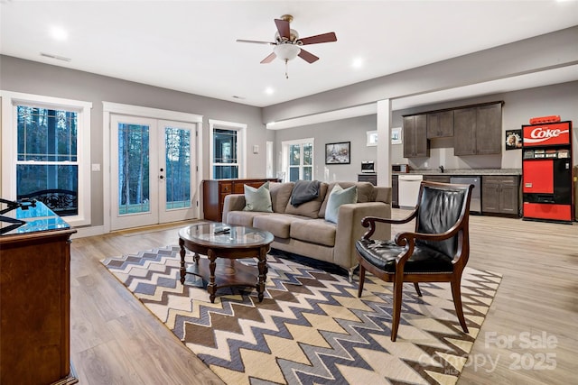 living area with light wood-style floors, visible vents, a ceiling fan, and french doors