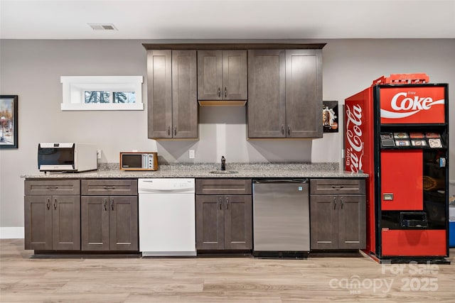 kitchen featuring light stone counters, visible vents, white dishwasher, a sink, and fridge