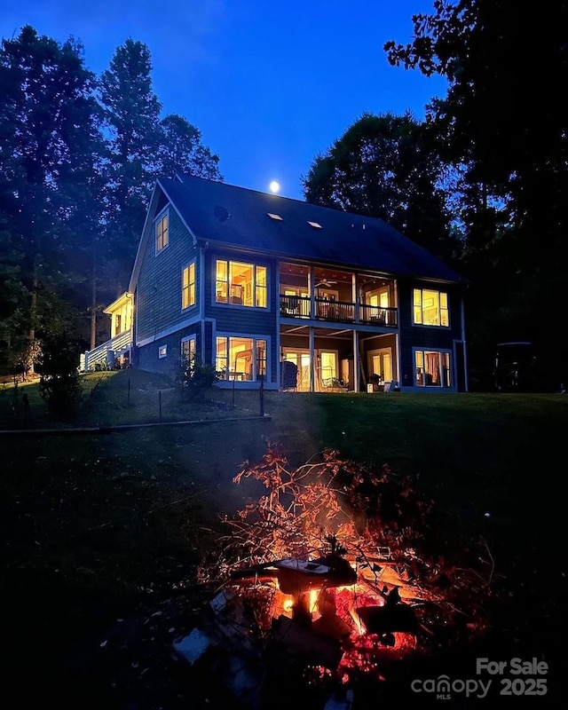 back of house at night featuring a balcony