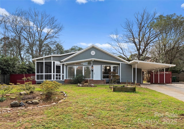 back of property featuring a lawn, a carport, and a sunroom