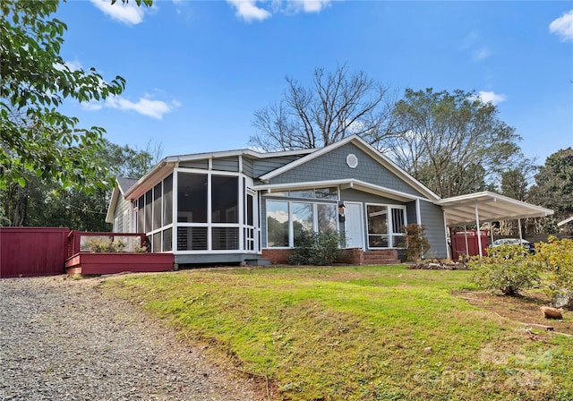 rear view of house featuring a lawn, a carport, and a sunroom