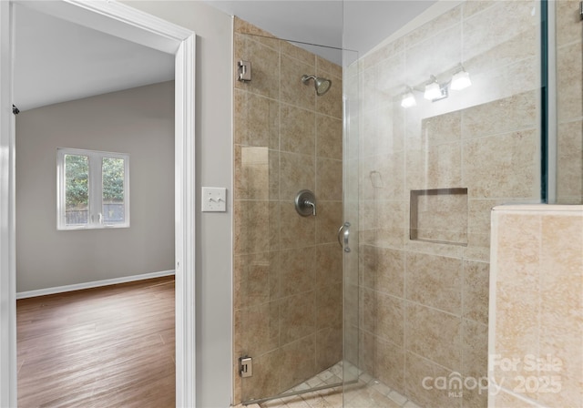 bathroom with lofted ceiling, tiled shower, and hardwood / wood-style floors