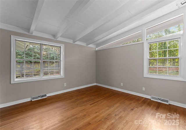 spare room with wood-type flooring and vaulted ceiling with beams