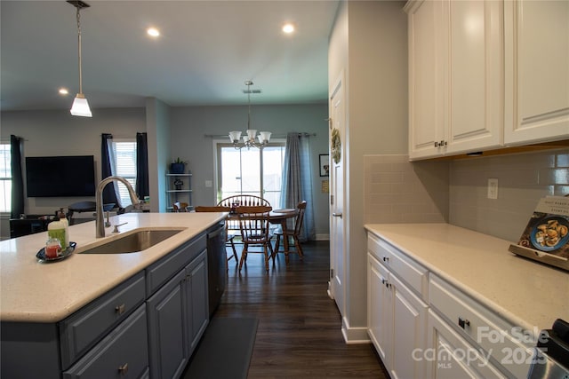 kitchen featuring pendant lighting, white cabinets, sink, and an inviting chandelier