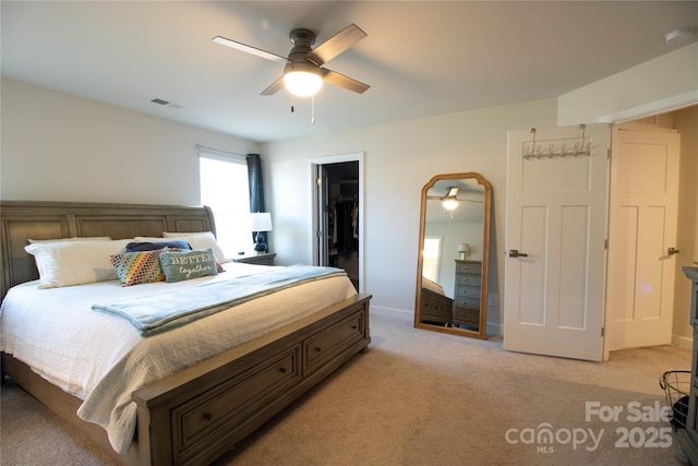 carpeted bedroom featuring a walk in closet, ceiling fan, and a closet