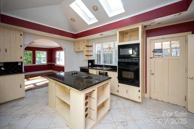 kitchen featuring a center island, lofted ceiling with skylight, backsplash, black appliances, and sink