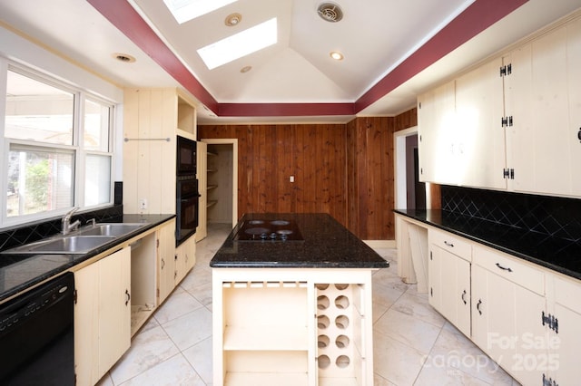 kitchen featuring a center island, wood walls, black appliances, sink, and a skylight