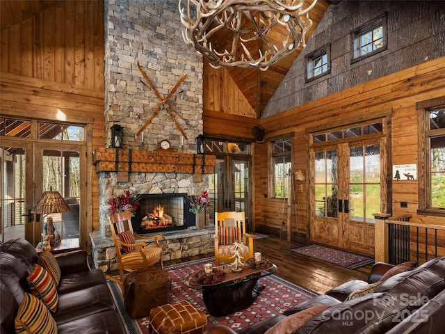 living room featuring french doors, plenty of natural light, high vaulted ceiling, and wood walls