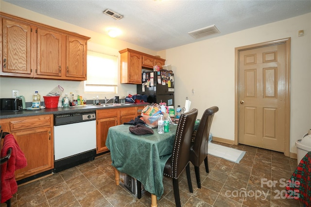 kitchen featuring black fridge, sink, a textured ceiling, and white dishwasher