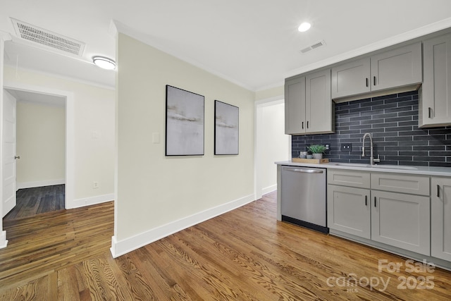 kitchen featuring sink, light hardwood / wood-style flooring, gray cabinets, dishwasher, and backsplash