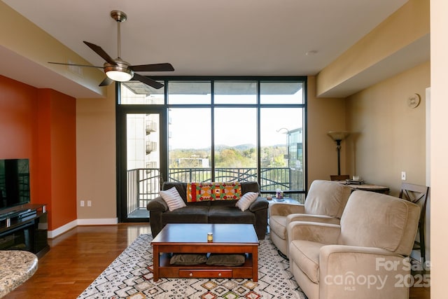 living room with hardwood / wood-style flooring, ceiling fan, and a wall of windows