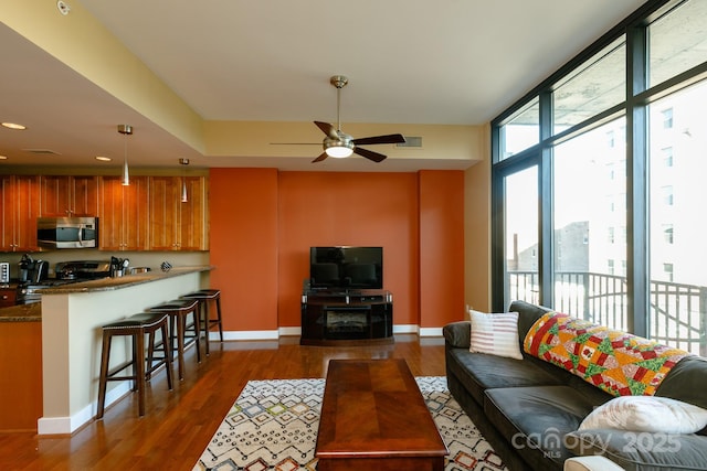 living room with floor to ceiling windows, ceiling fan, and dark wood-type flooring