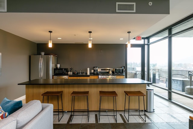 kitchen with stainless steel fridge, a kitchen breakfast bar, and pendant lighting