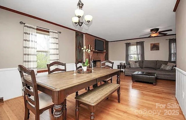 dining space featuring ceiling fan with notable chandelier, light hardwood / wood-style floors, and crown molding