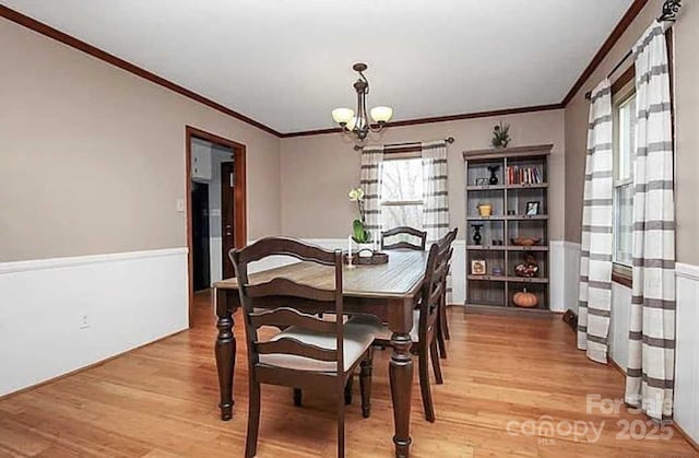 dining space featuring hardwood / wood-style floors, crown molding, and a notable chandelier