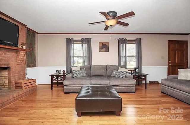 living room with crown molding, ceiling fan, a fireplace, plenty of natural light, and light hardwood / wood-style floors