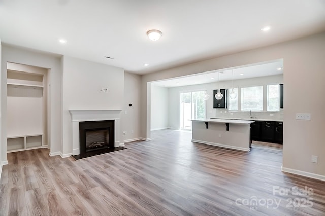 unfurnished living room with light hardwood / wood-style flooring and sink