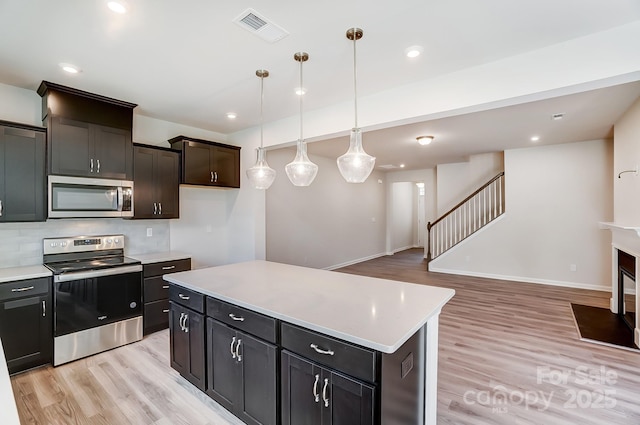 kitchen featuring a center island, hanging light fixtures, stainless steel appliances, tasteful backsplash, and light hardwood / wood-style flooring