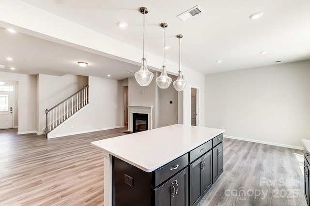 kitchen with a kitchen island, light hardwood / wood-style floors, and decorative light fixtures