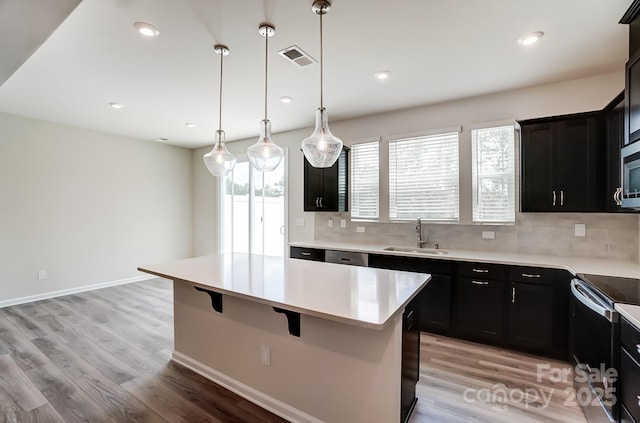 kitchen with a center island, sink, stainless steel appliances, pendant lighting, and decorative backsplash