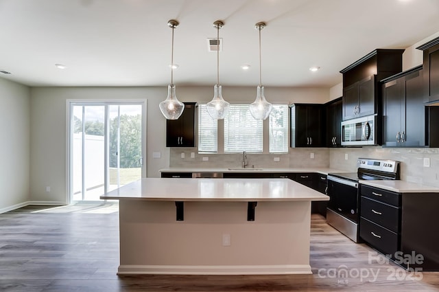 kitchen with sink, a center island, tasteful backsplash, decorative light fixtures, and appliances with stainless steel finishes