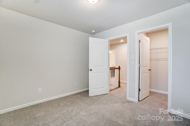 unfurnished bedroom with light colored carpet, a walk in closet, and a closet