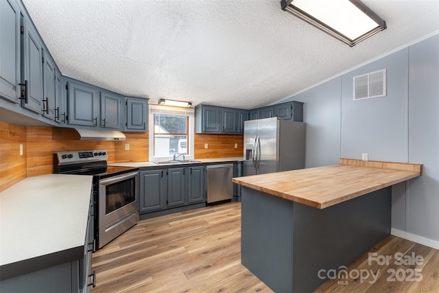 kitchen featuring butcher block counters, sink, kitchen peninsula, crown molding, and appliances with stainless steel finishes