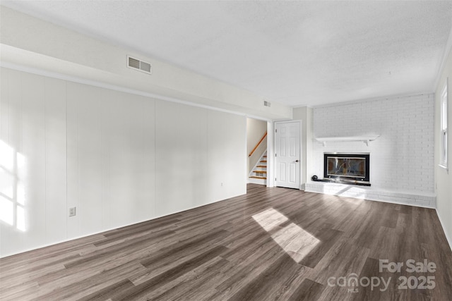 unfurnished living room with a fireplace, wood-type flooring, and a textured ceiling