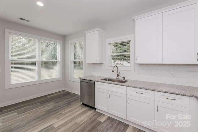 kitchen featuring white cabinets, dishwasher, light stone counters, and sink