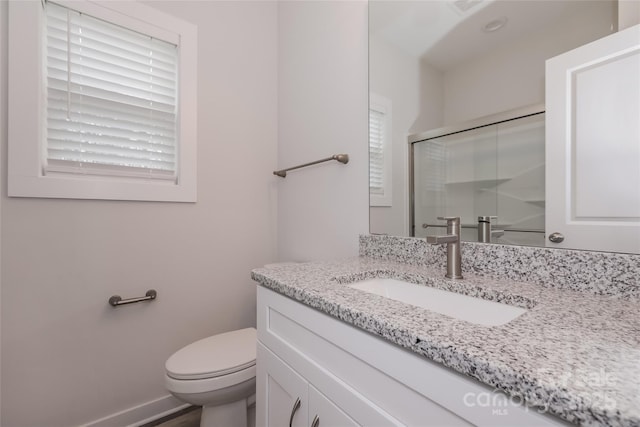 bathroom with a healthy amount of sunlight, an enclosed shower, vanity, and toilet