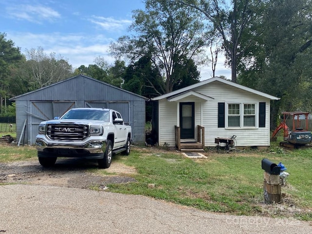 view of front of home with a garage, an outbuilding, and a front lawn