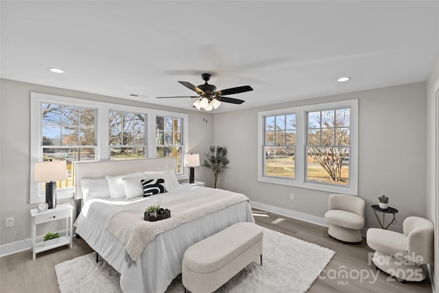 bedroom featuring multiple windows, dark wood-type flooring, and ceiling fan