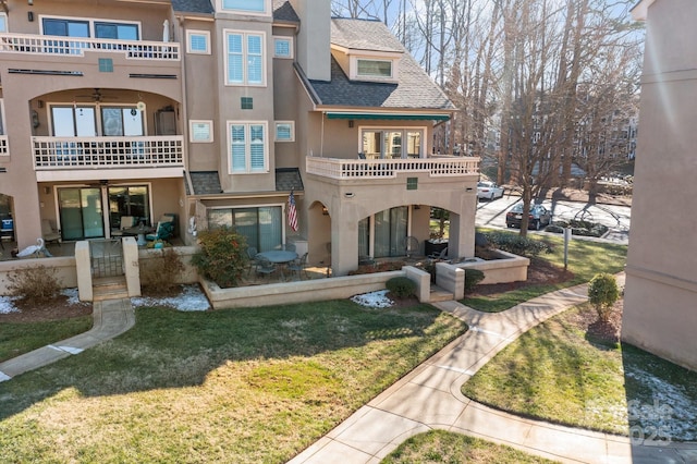 back of house featuring a balcony and a lawn