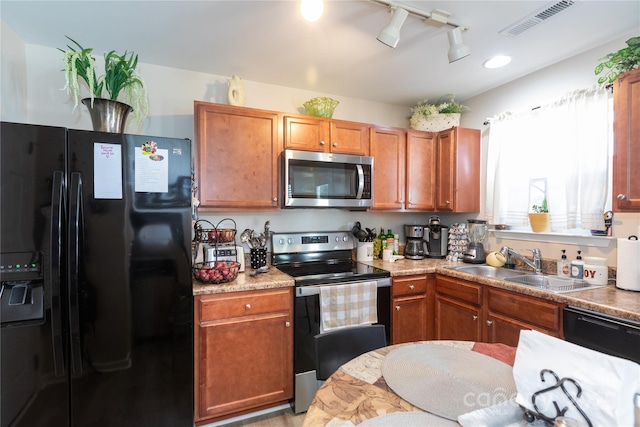 kitchen with sink, rail lighting, black appliances, and light stone countertops