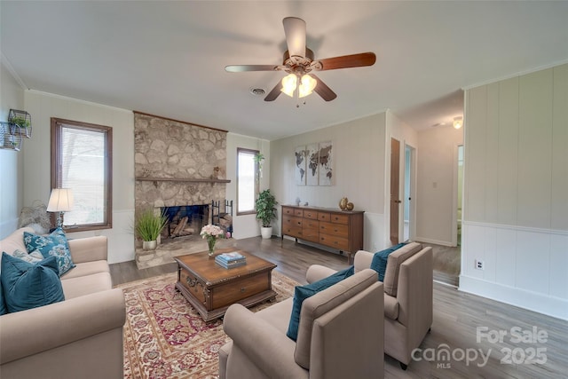 living room with hardwood / wood-style floors, a stone fireplace, and ceiling fan