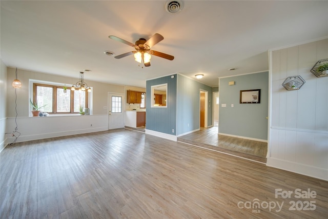 unfurnished living room with ornamental molding, ceiling fan with notable chandelier, and hardwood / wood-style flooring