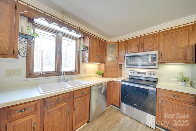 kitchen featuring crown molding, sink, stainless steel appliances, and light hardwood / wood-style flooring