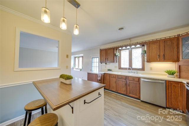 kitchen featuring pendant lighting, a breakfast bar, sink, stainless steel dishwasher, and a wealth of natural light