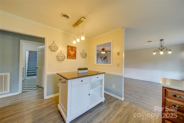 kitchen with ornamental molding, pendant lighting, light hardwood / wood-style flooring, white cabinets, and a center island