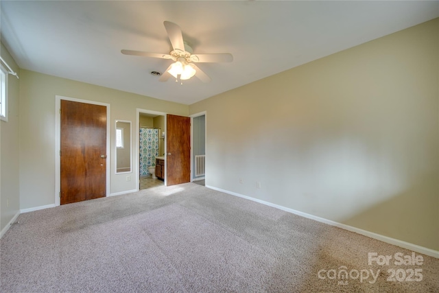 unfurnished bedroom featuring carpet, connected bathroom, multiple windows, and ceiling fan