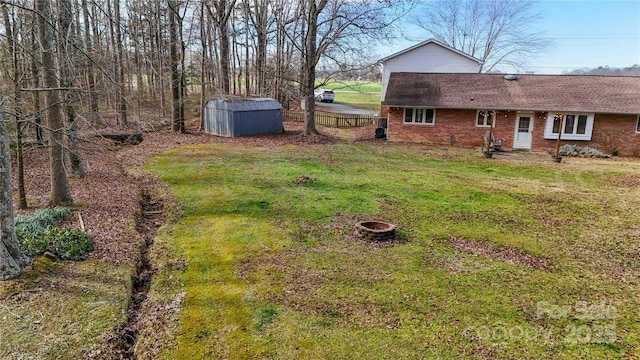 view of yard featuring an outdoor fire pit and a storage shed