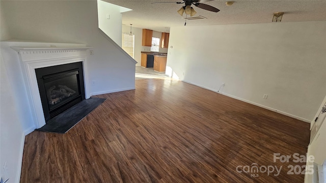 unfurnished living room with a textured ceiling, ceiling fan, and dark wood-type flooring