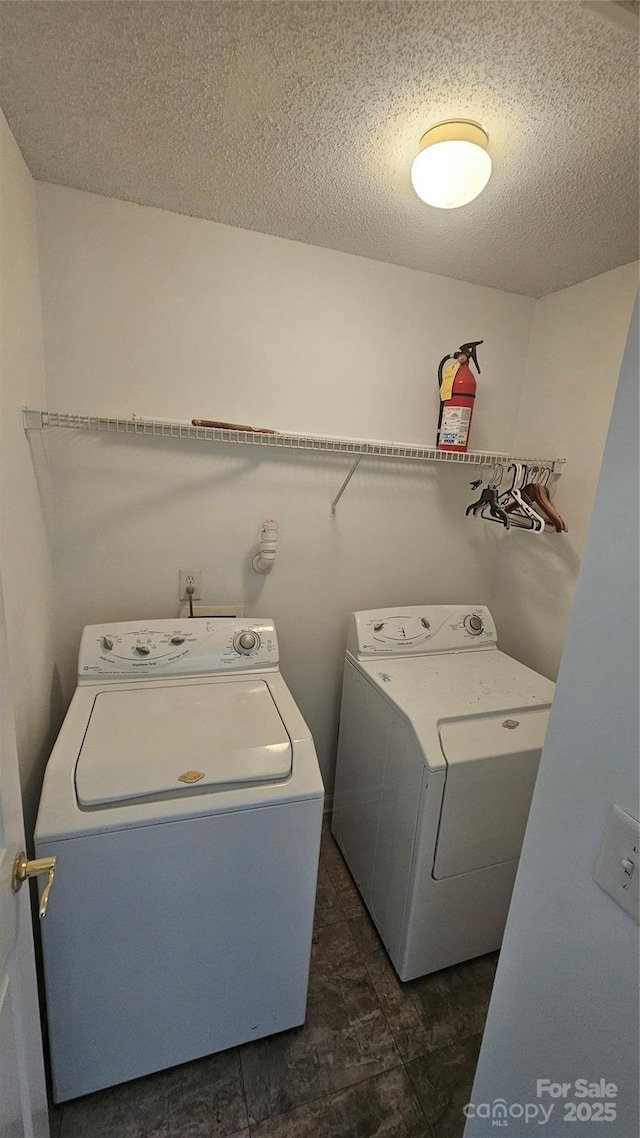 washroom featuring a textured ceiling and washing machine and dryer