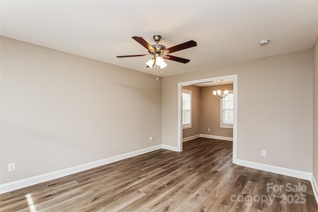 empty room with ceiling fan with notable chandelier and dark wood-type flooring