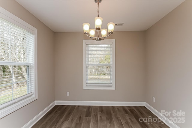 unfurnished room with a notable chandelier and dark hardwood / wood-style floors