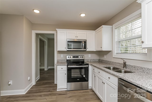 kitchen with stainless steel appliances, light stone countertops, dark hardwood / wood-style floors, sink, and white cabinetry