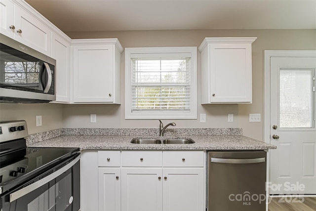 kitchen with appliances with stainless steel finishes, white cabinetry, and sink