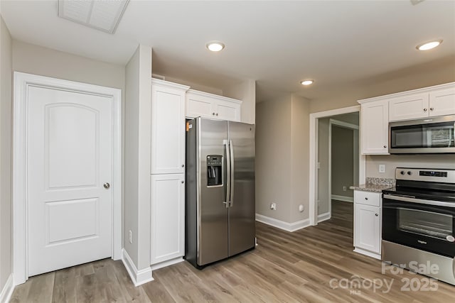 kitchen with light stone counters, stainless steel appliances, light wood-type flooring, and white cabinetry