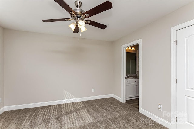 unfurnished bedroom with ensuite bath, ceiling fan, and dark carpet