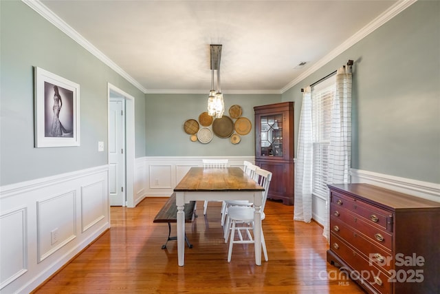 dining room with light hardwood / wood-style floors and crown molding